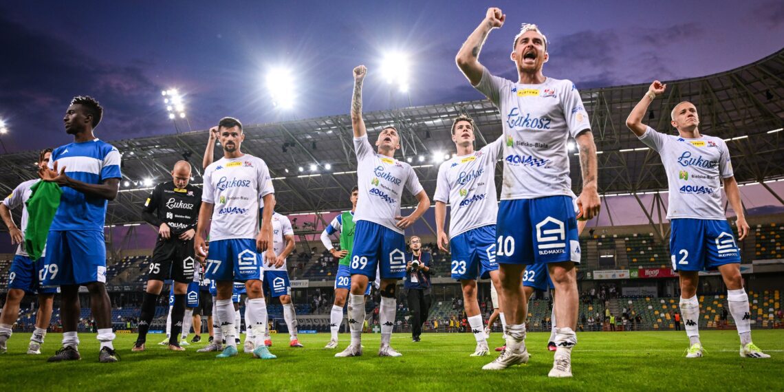 grupa piłkarzy podbeskidzia cieszących się ze zwycięstwa na stadionie piłkarskim